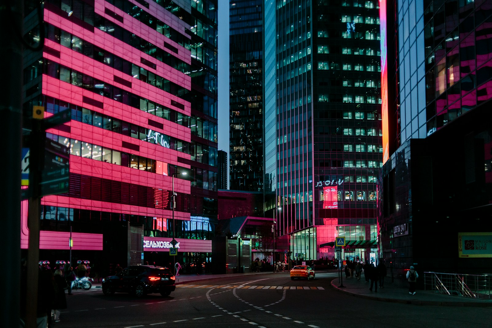Vibrant city street at night with pink lights.